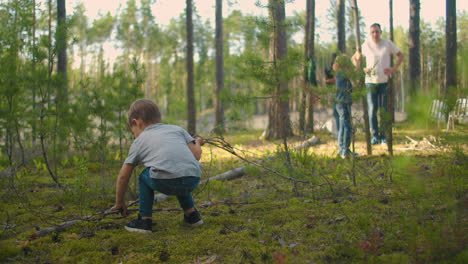 Two-little-boy-collecting-firewood-in-the-forest.-Two-little-brothers-in-the-forest-gather-wood-together-and-build-a-fire
